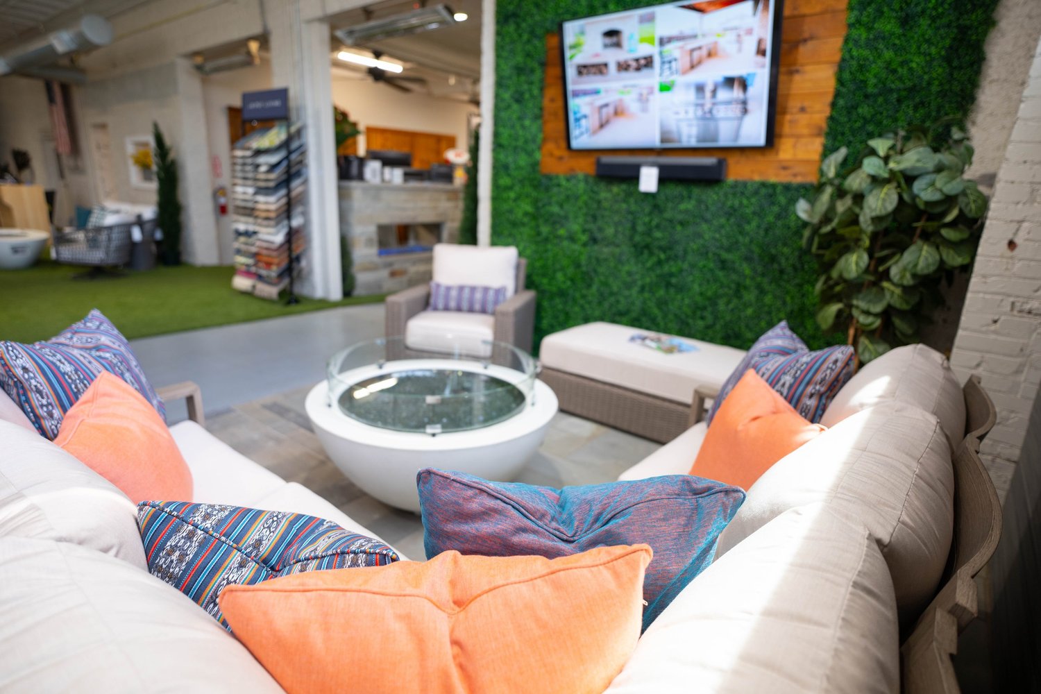 Showroom vignette with lounge seating, fire table, wall TV and turf wall