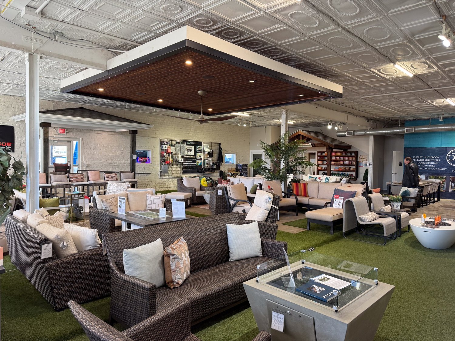 Showroom floor with lounge sets and fire tables under a suspended wood ceiling
