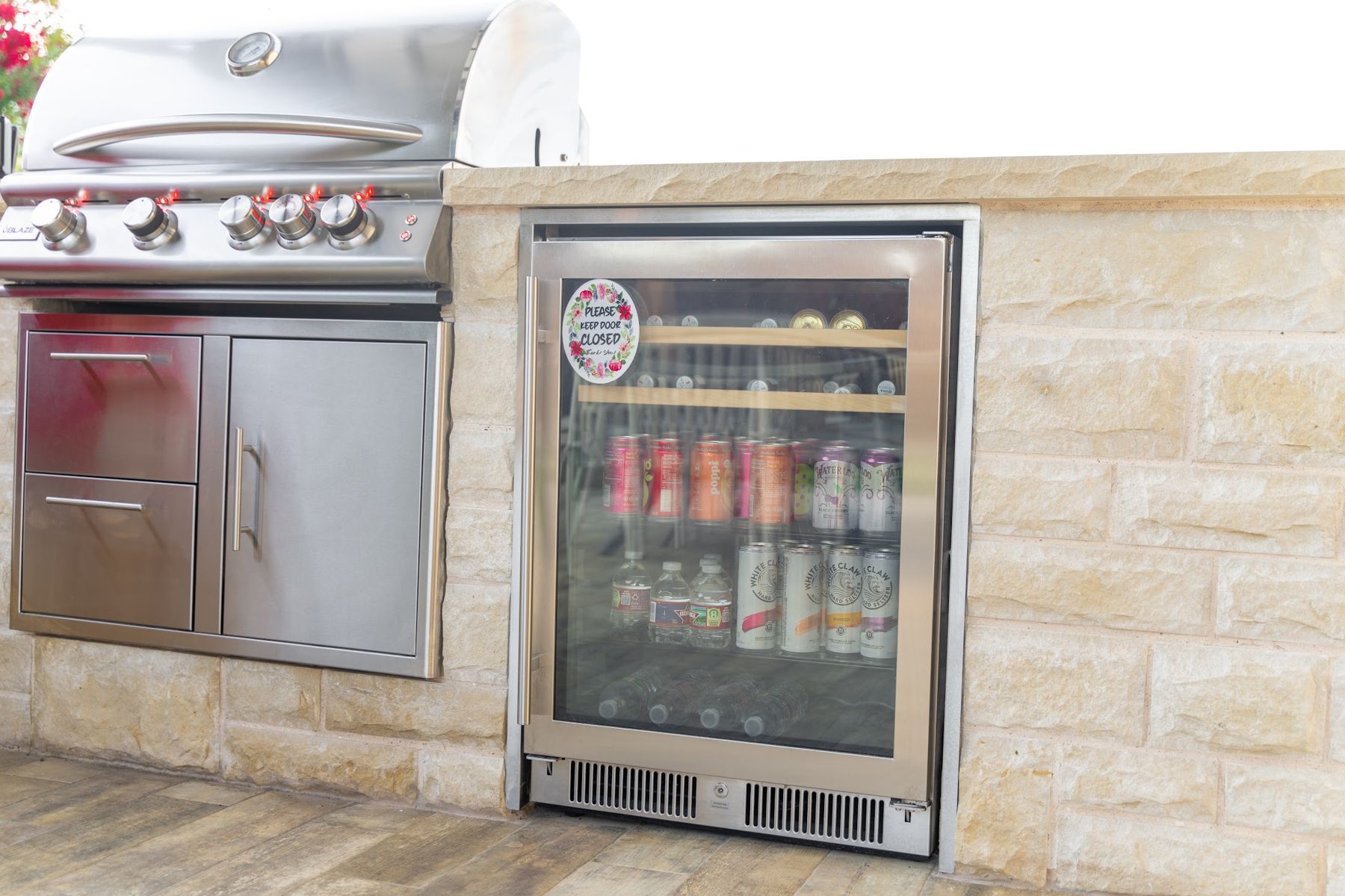 Built-in grill, stainless doors and glass-front beverage fridge set into a limestone island, Aledo