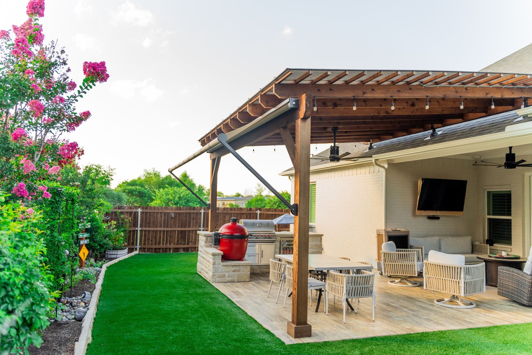 Cedar pergola over an outdoor kitchen with kamado, grill and dining set on turf, Aledo