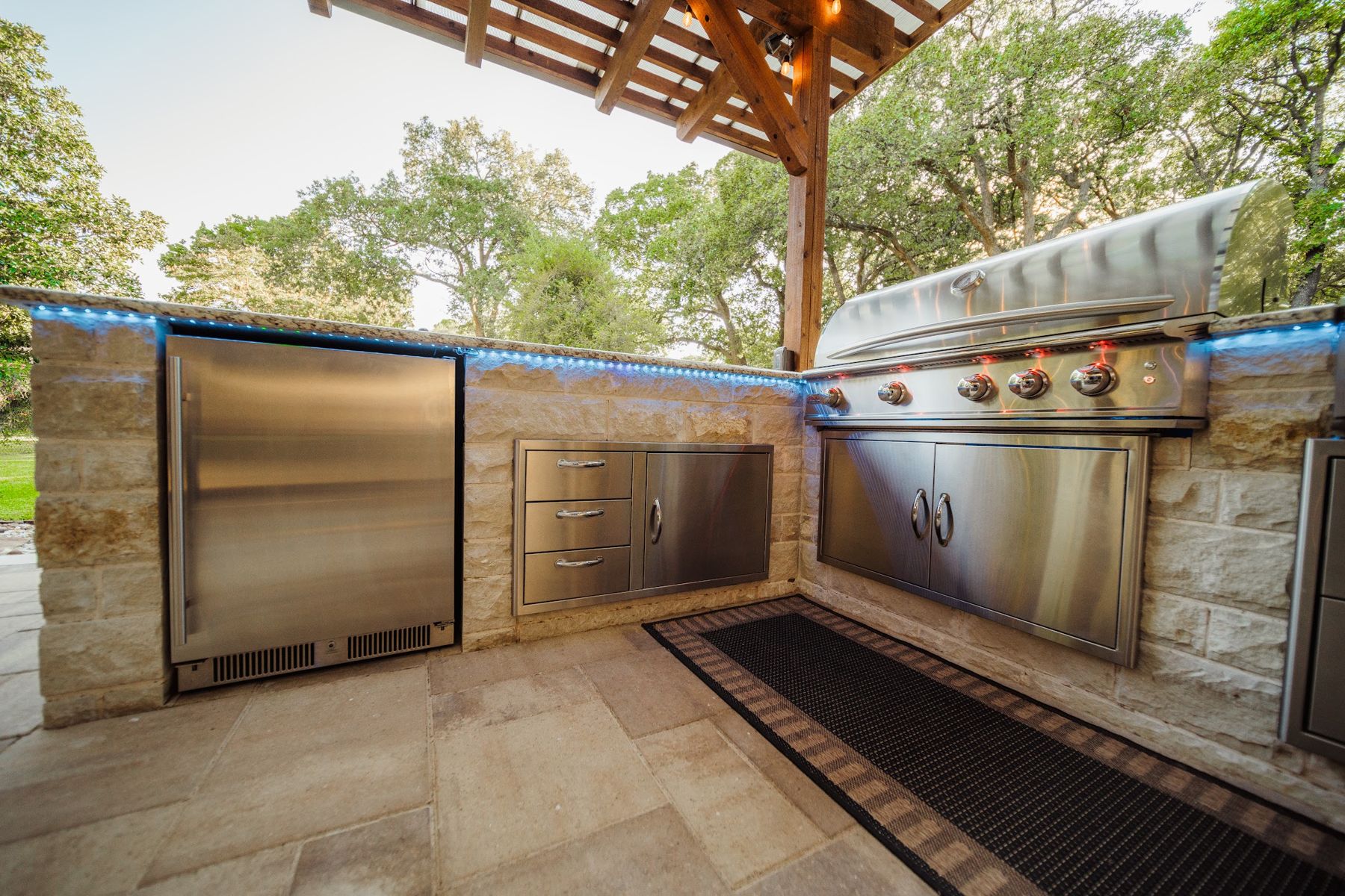 Stainless refrigerator, access doors and grill set into a stone kitchen run