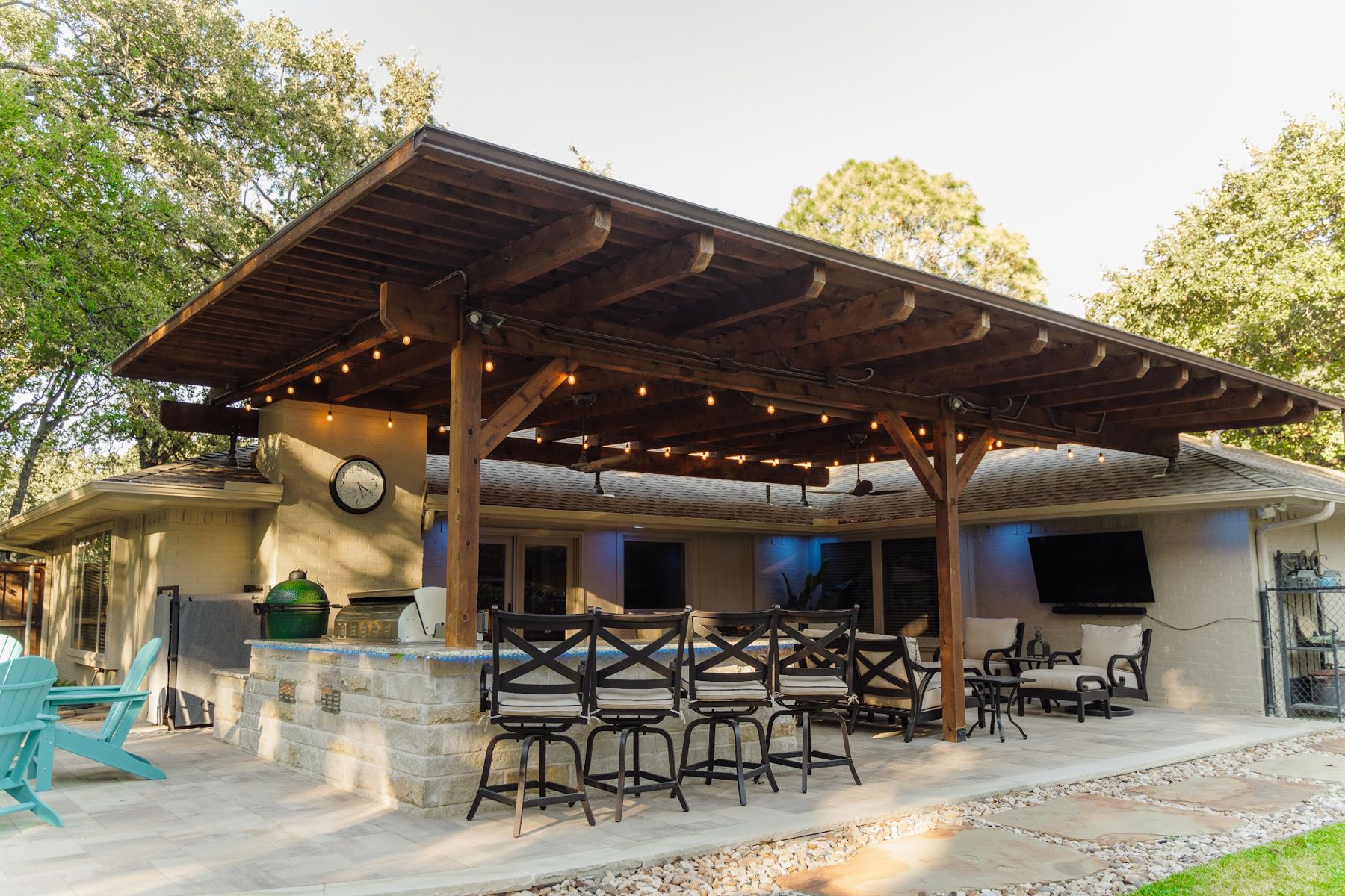 Timber pavilion with string lights over a stone kitchen bar and bar stools, Arlington