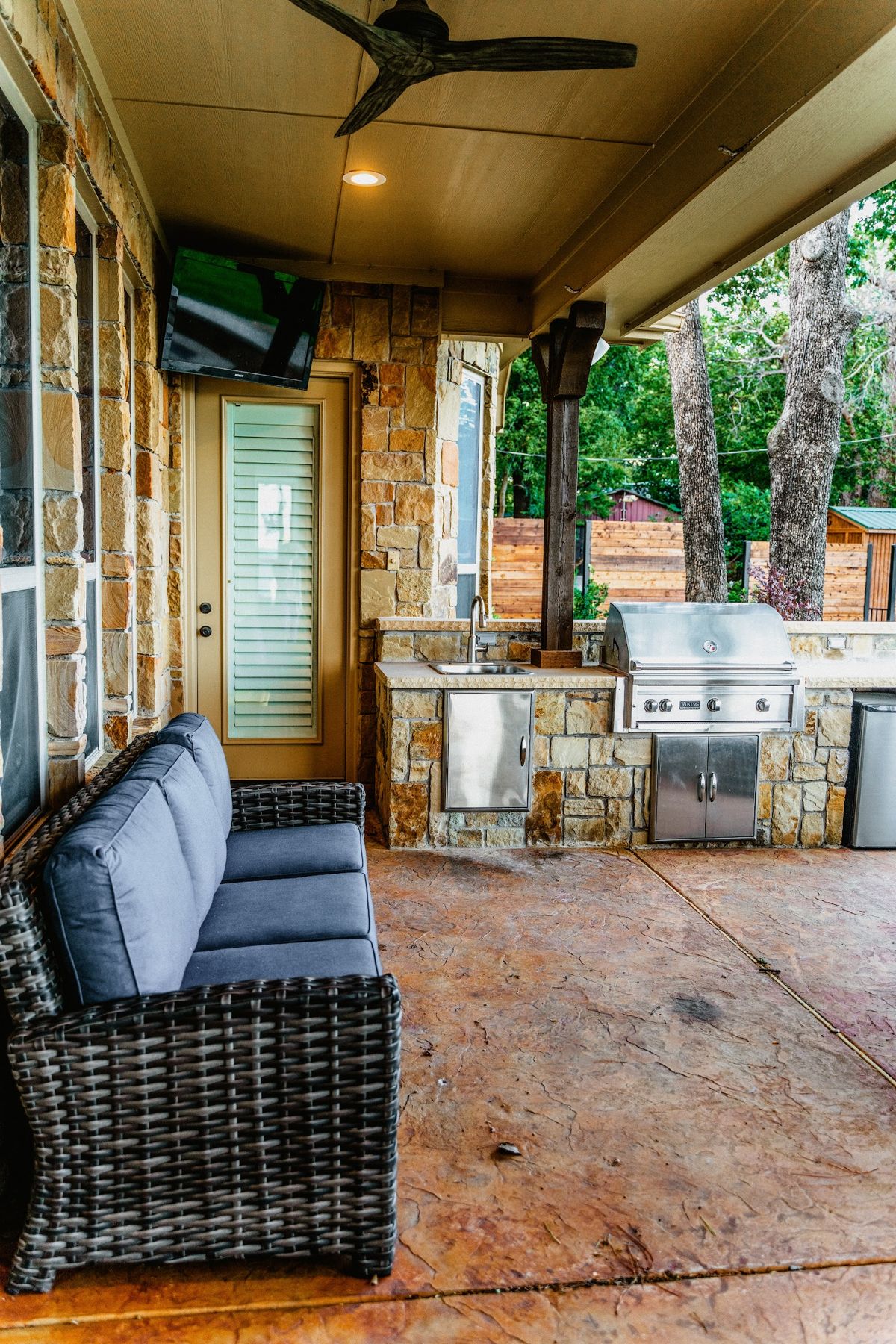 Covered stone outdoor kitchen with built-in grill and sectional seating, Eagle Mountain Lake