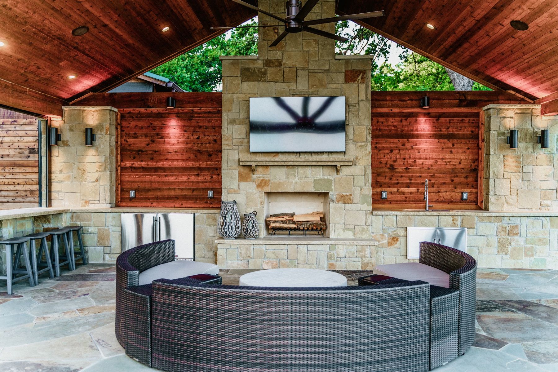 Finished pavilion with stone fireplace, TV, cedar walls and curved sectional