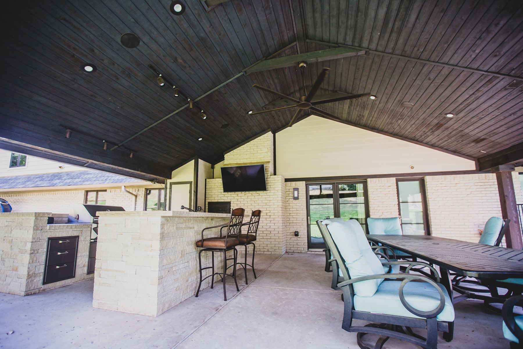 Gable patio cover with limestone kitchen island, bar stools, TV and dining set, Fort Worth