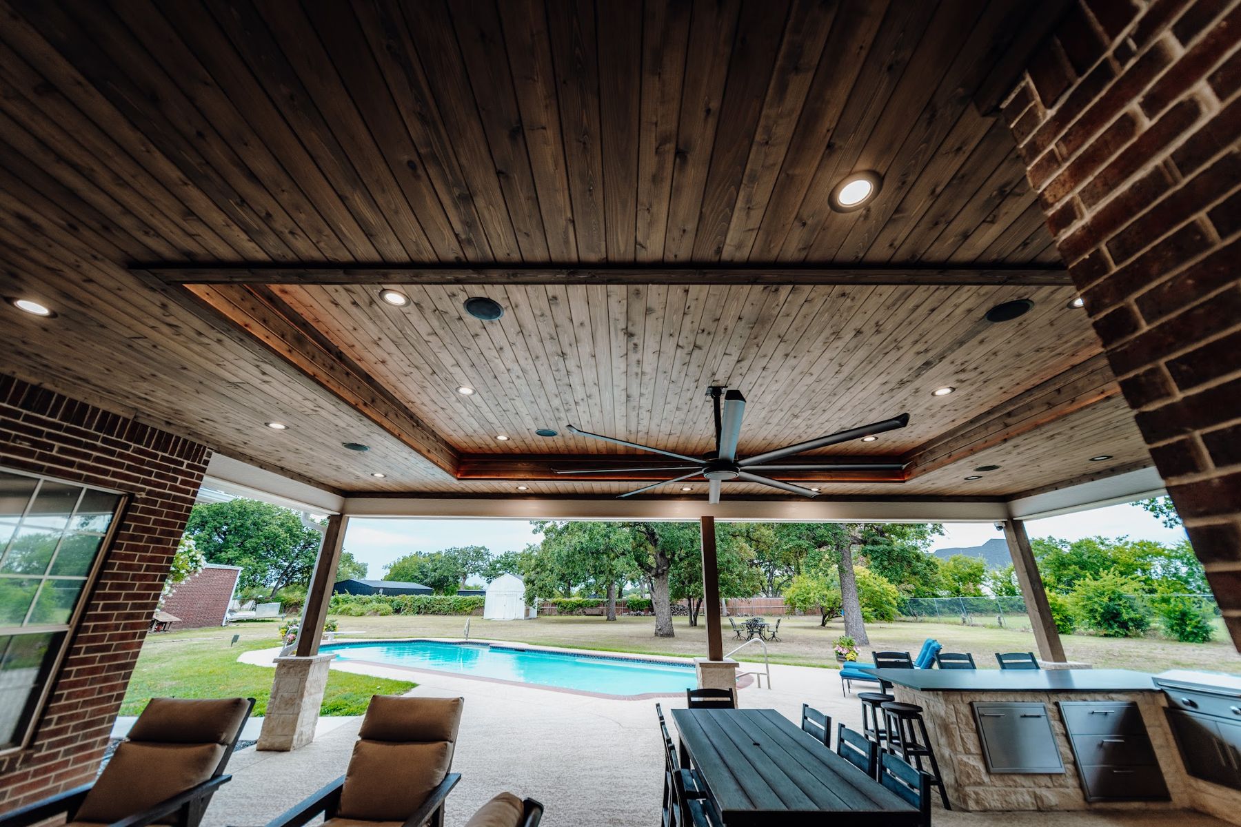 Cedar ceiling with LED cove lighting and fan over a pool view, Keller
