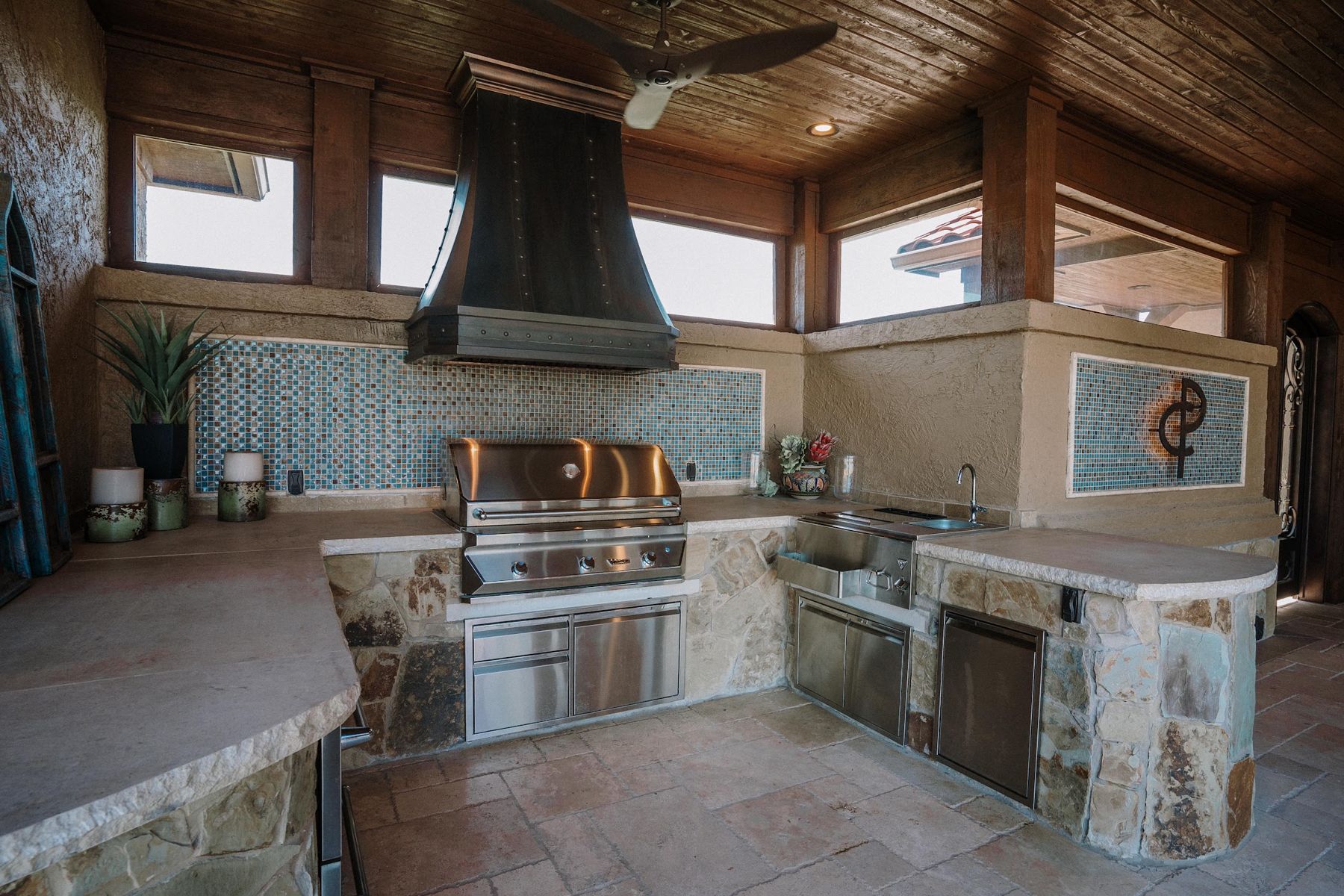 Outdoor kitchen with copper range hood, tile backsplash and built-in grill